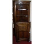 A joined and floral relief carved oak freestanding corner cupboard, the open shelving over