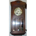 A 1920s mahogany droptrunk wall clock, with pendulum