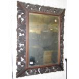 An early 20th century floral relief carved and pierced oak framed bevelled rectangular wall