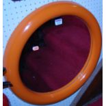 A 1970s orange painted fibreglass framed cushion circular wall mirror, dia.52cm