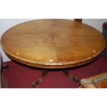 A Victorian faded figured walnut oval tilt-top pedestal breakfast table, raised on floral carved and