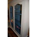 An early 20th century and later grey painted double door glazed book case with squat bun supports,