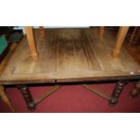 A large early 20th century oak drawer leaf dining table, raised on heavy part barley twist turned