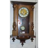 An early 20th century figured walnut Vienna droptrunk wall clock, with pendulum
