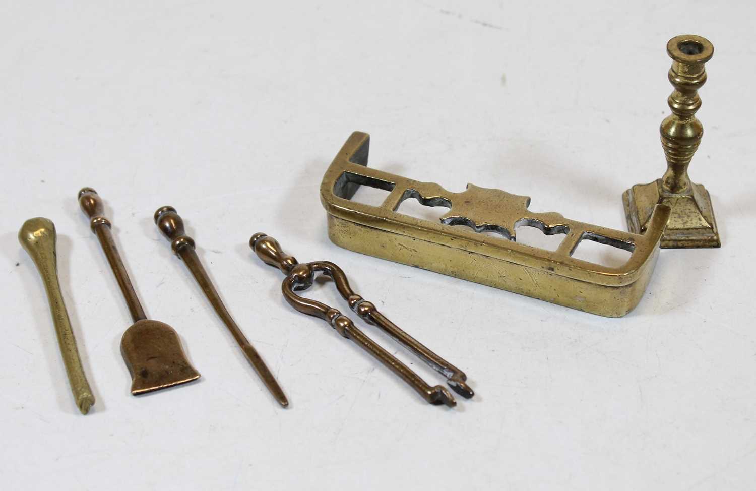A miniature brass fire fender; together with miniature fire tongs, poker, shovel, and candlestick