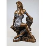 A contemporary gilt and silver painted plaster figure of a seated lady shown reclining on a rock,