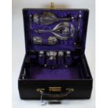 A George V ladies black leather vanity case, the hinged lid opening to reveal a purple silk lined