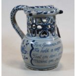 An 18th century English Delft puzzle jug, bearing verse 'Here Gentlemen come try your skill, I'll