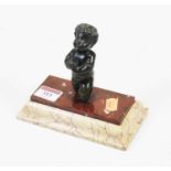 A small bronze figure of a cherub, in kneeling pose on a rouge and veined marble stepped plinth