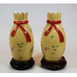 A pair of Chinese export yellow glazed vases, decorated with flowers, on associated carved wooden