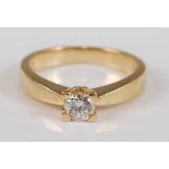 A yellow metal diamond single stone ring, featuring a round brilliant cut diamond in a four-claw V-