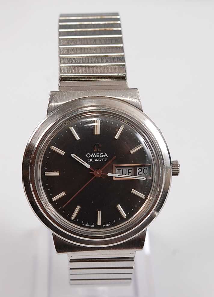 A Gents stainless steel Omega Mega-Quartz wristwatch, with round black baton dial and day/date at