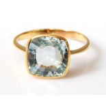 A yellow metal aquamarine single stone ring, featuring a cushion shaped aquamarine in a bezel