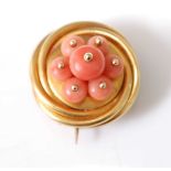 A yellow metal circular coral memorial brooch, comprising a three strand overlapping border with a