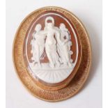 A 9ct yellow gold oval shell cameo brooch depicting The Three Graces, in a bezel setting with