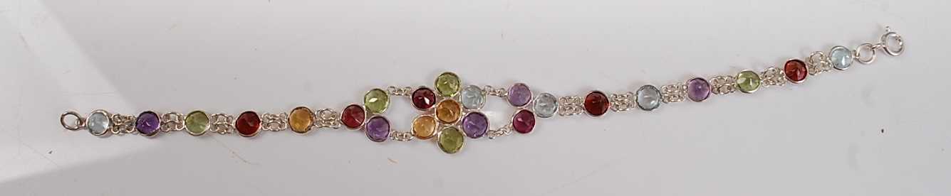 A white metal flower design multi-stone bracelet, having 6 round garnets, 5 round peridots, 5