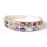 A white metal multi-stone oval hinged bangle, set with the following stones; two sapphires, total