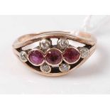 A 9ct gold, ruby and diamond dress ring, the elliptical setting centre set with three round cut