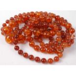 A clear orange amber beaded and knotted necklace, with gilt metal clasp; and one other beaded and