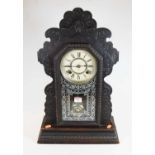 An early 20th century American gingerbread mantel clock, the painted dial showing Roman numerals,