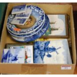 A box containing a collection of Dutch tiles and dishes