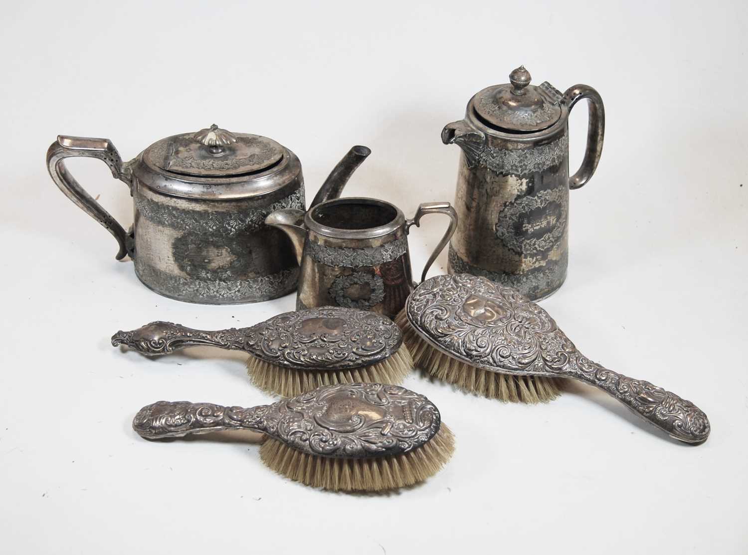 Three various circa 1900 silver backed brushes; together with a Walker & Hall silver plated three-