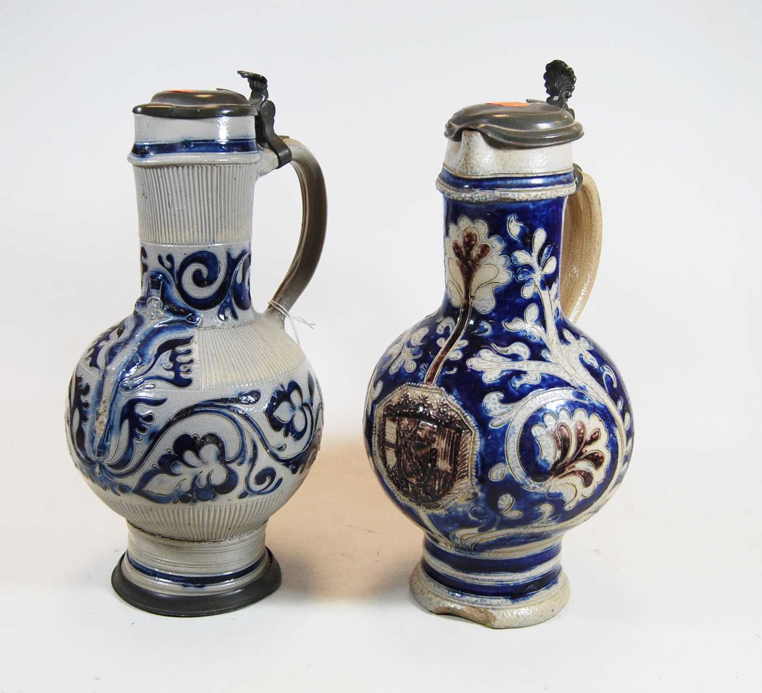 A German Westerwald stoneware jug, with pewter lid and thumb rest decorated in blue with a crucifix,