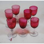 Five Victorian cranberry glass wine hocks, each having a plain bowl on a faceted stem and domed