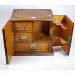 An early 20th century oak smoker's cabinet, the doors opening to reveal fitted interior with an