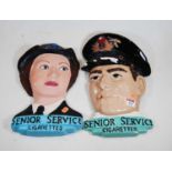 A near pair of plaster advertising wall plaques, each with mask of a service person, and inscribed