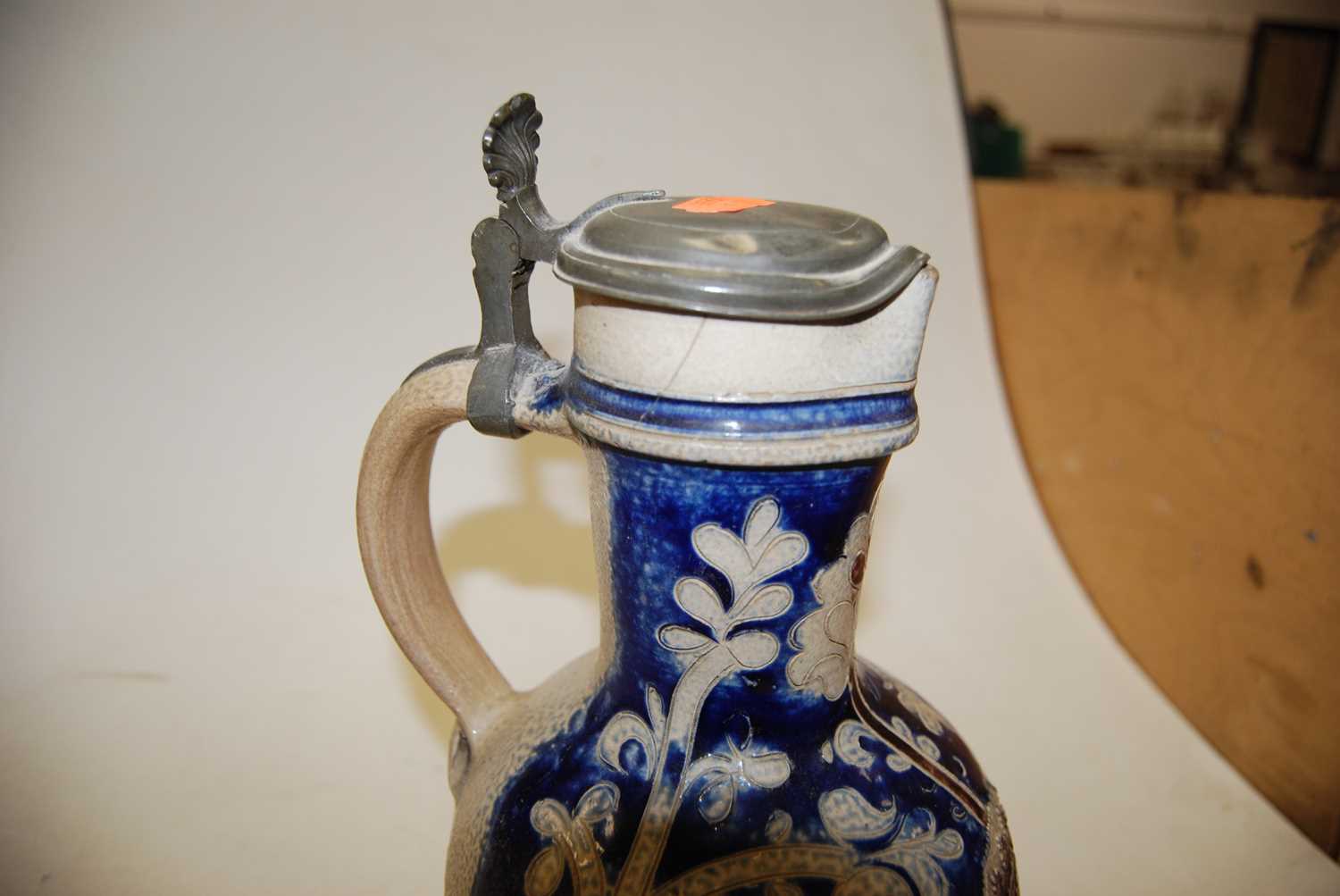 A German Westerwald stoneware jug, with pewter lid and thumb rest decorated in blue with a crucifix, - Image 10 of 14