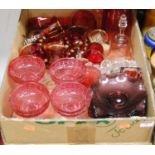 A box containing a collection of cranberry glass ware to include a water jug, ice cream bowls, and