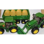 An Ertl plastic John Deere tractor and trailer, together with one other with farrow