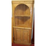 A reclaimed pine corner cupboard, the arched open compartment with shaped fixed shelf over single