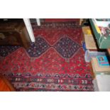 A Persian woollen red ground Shiraz rug, the central medallions within trailing tramline borders,