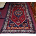 A Persian hand-woven woollen red ground Shiraz rug, 240 x 125cm
