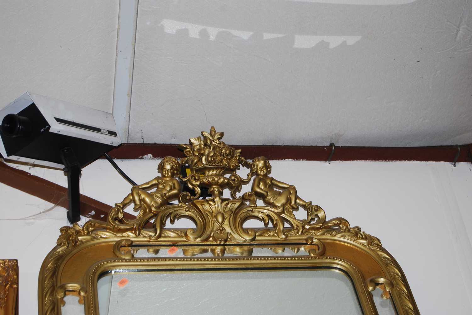 A gilt composition framed wall mirror having cherub and basket of flowers surmount and a moulded - Image 2 of 2