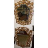 A pair of decorative Baroque style floral pierced and gilded framed shaped wall mirrors, each 88 x