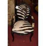A French ebonised and carved showframe fauteuil, upholstered in faux zebra hide, in the Louis XV