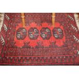 A Persian woollen red ground small bokhara rug, 73 x 52.5cm