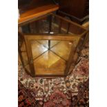 An early 20th century oak and polished brass mounted low corner retailers display cabinet, having
