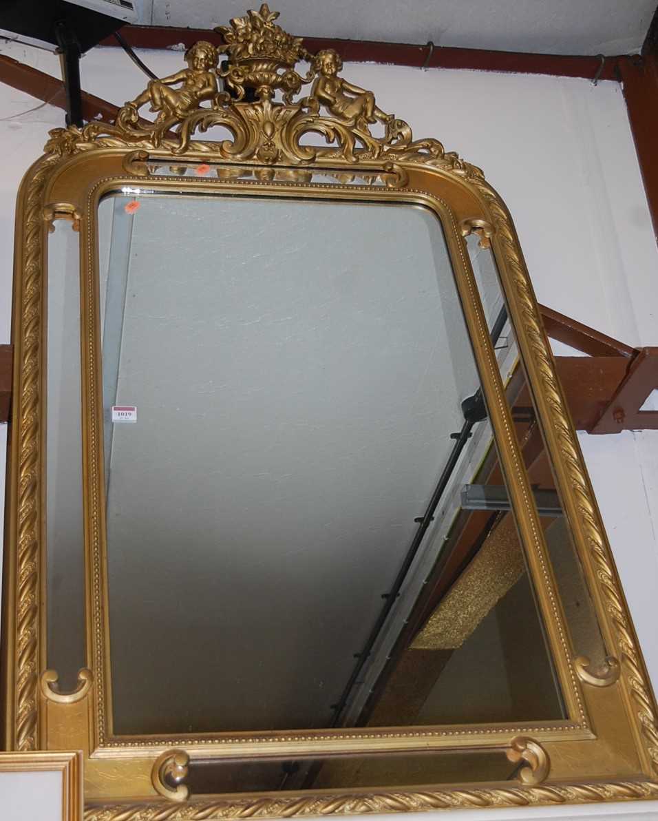 A gilt composition framed wall mirror having cherub and basket of flowers surmount and a moulded