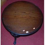 A contemporary circular oak topped low occasional table, raised on black enamelled cast metal