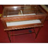 A faded walnut and glazed retailers display cabinet, raised on integral stand with hinged rear door,