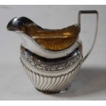 A late Victorian silver cream jug, of helmet shape and half-gadrooned form, having angular handle