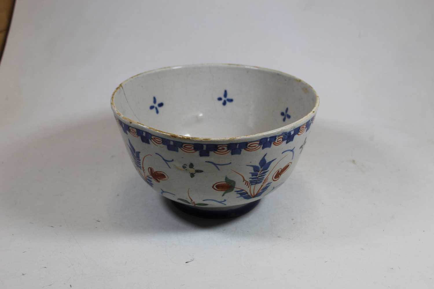 An 18th century English Delft bowl, decorated in shades of blue, brown and green, on circular foot - Image 2 of 3