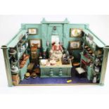 A dolls house single room shop/diorama, fitted with various pies, loaves, tins, and pictures, the
