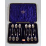 A cased set of twelve early 20th century silver teaspoons and a pair of sugar nips, with scroll