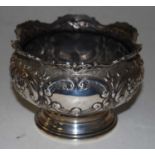 An Edwardian silver bowl having wavy rim and squat circular body, repousse decorated with flowers