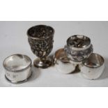 An Edwardian silver egg cup, having repousee floral decoration and initialled cartouche; together